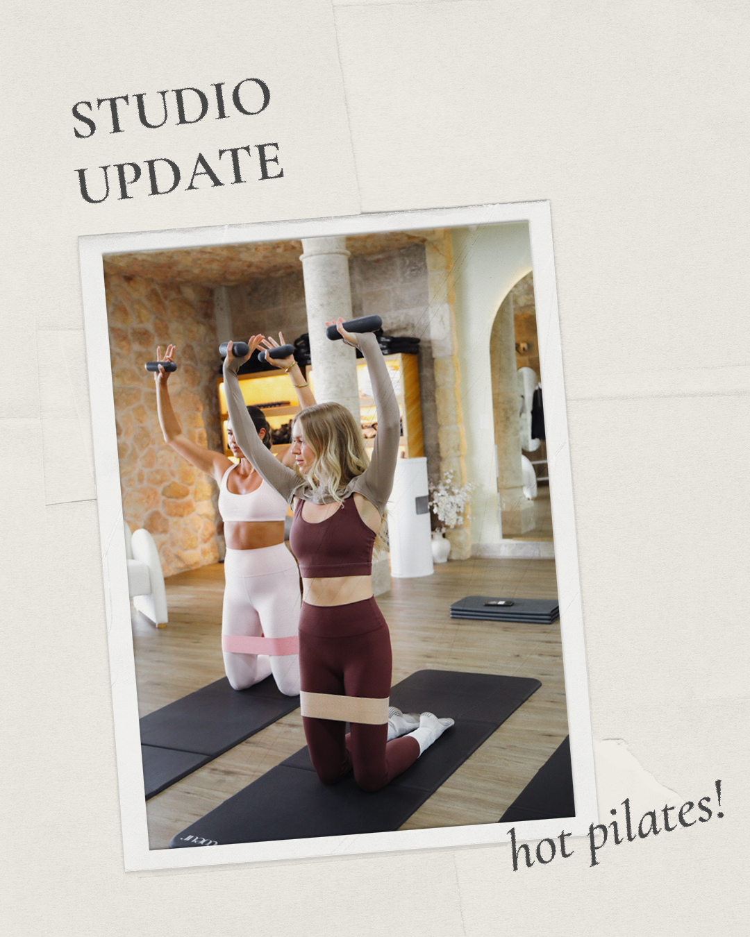 Two women in athletic wear practicing Pilates with resistance bands on kneeling mats in a studio with brick and stone walls.