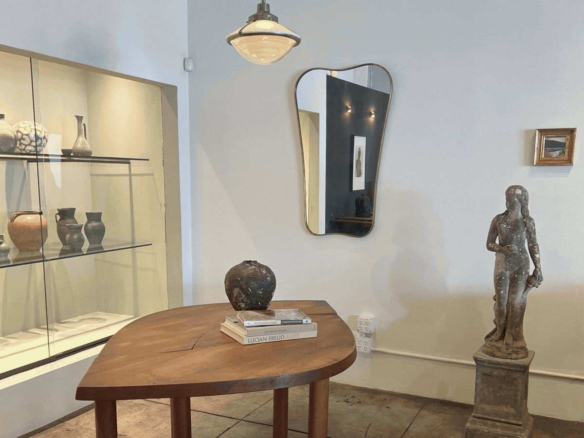 Interior of an vintage furniture showroom and gallery in Los Angeles, a stone sculpture at Francis Gallery, and bookshelves, a female interior designer, an LA based creative director, a Boise Interior Designer and display shelves with pottery.