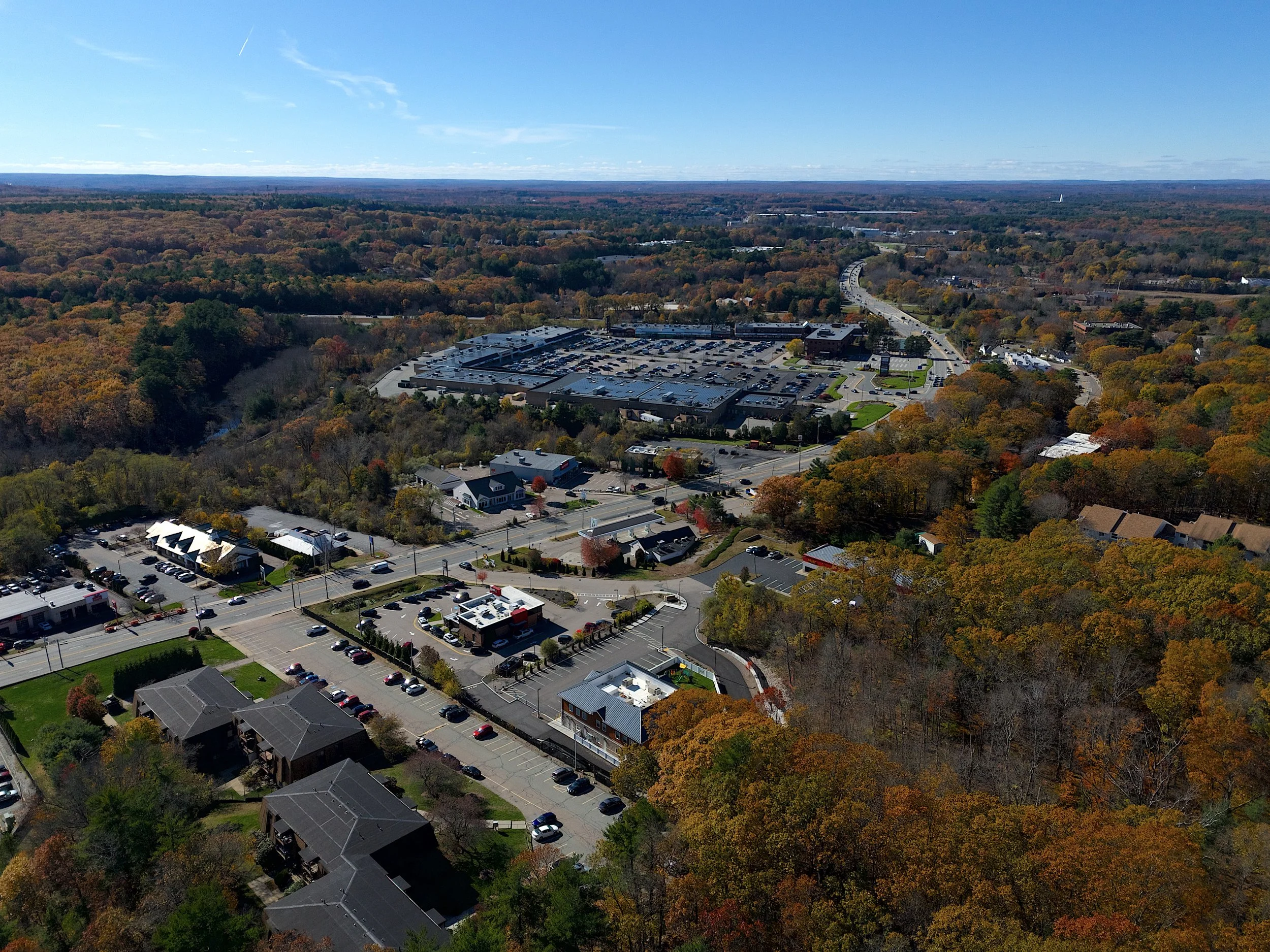 Marketing aerial, drone photo in the town of Franklin, Massachusetts of a day care center with blue skies, foliage and highways with commercial property surrounding the day care center.