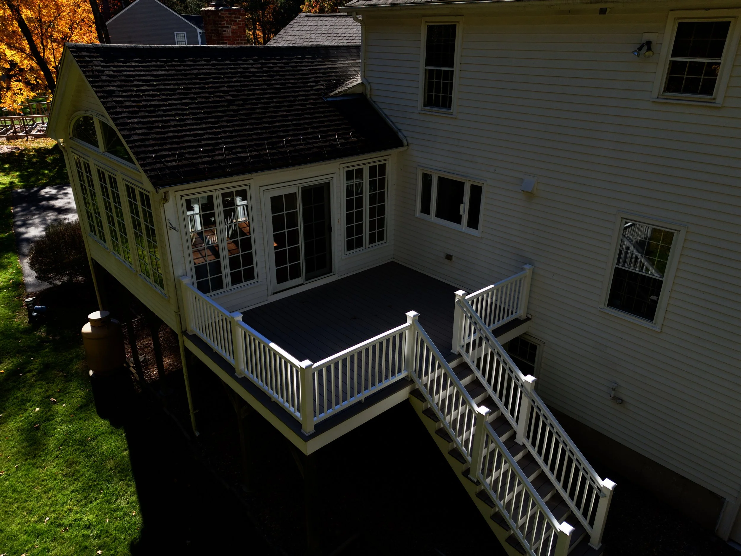 Real estate aerial, drone photography of a house in Sudbury, Massachusetts in a residential neighborhood with blue skies, a lake and foliage near Boston.