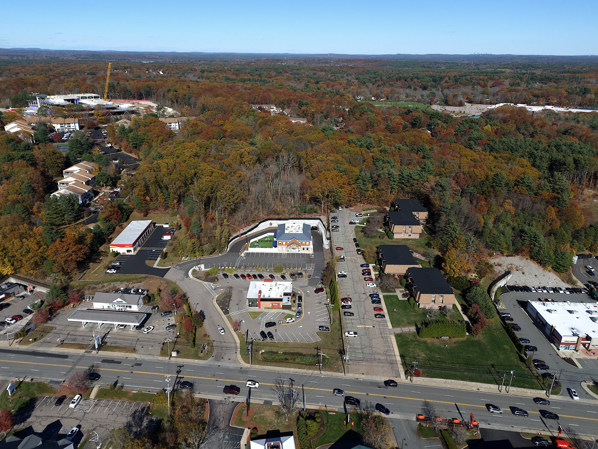 Marketing aerial, drone photo in the town of Franklin, Massachusetts of a day care center with blue skies, foliage and highways with commercial property surrounding the day care center.