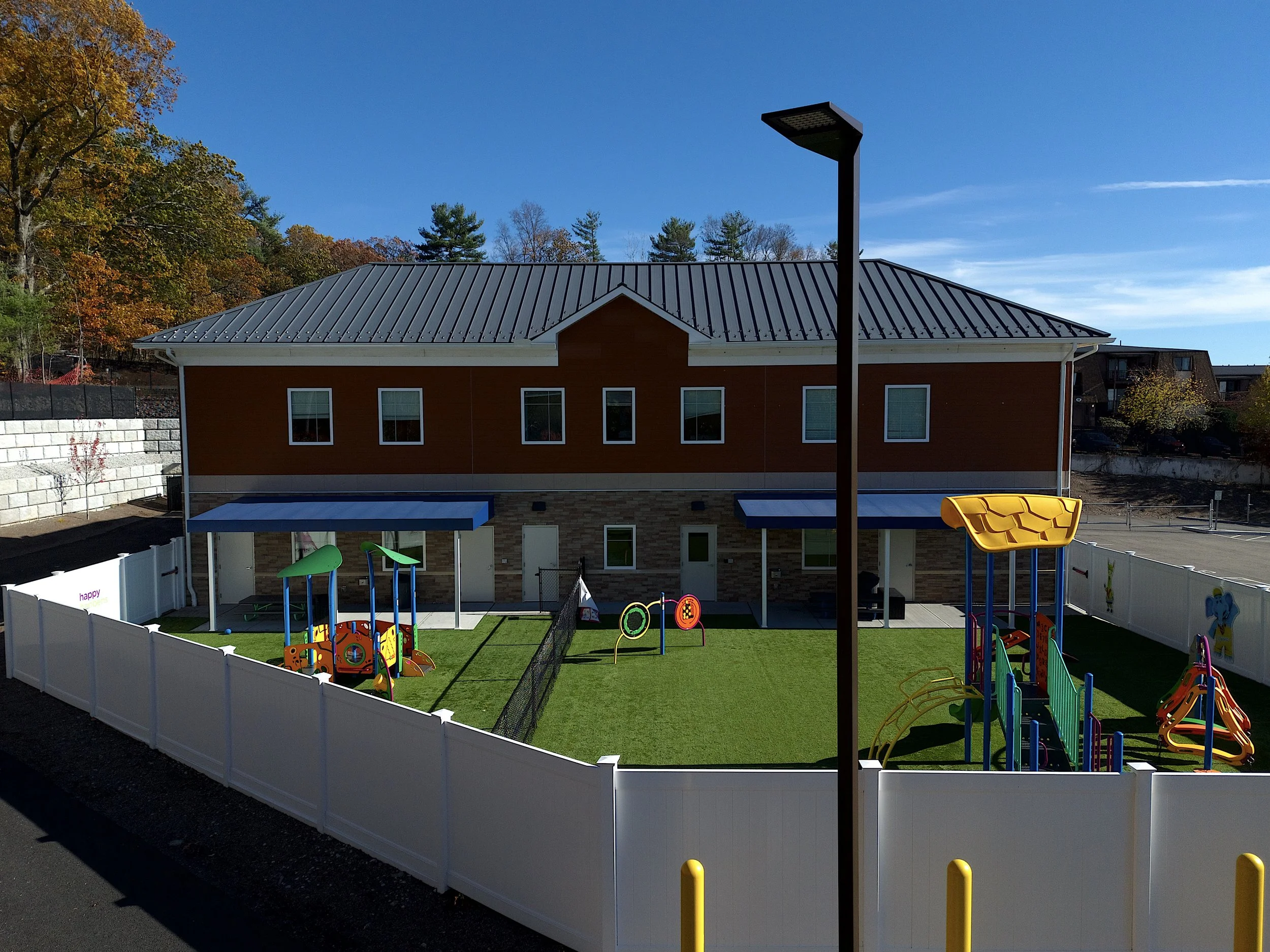 Marketing aerial, drone photo in the town of Franklin, Massachusetts of a day care center with blue skies, foliage and highways with commercial property surrounding the day care center.