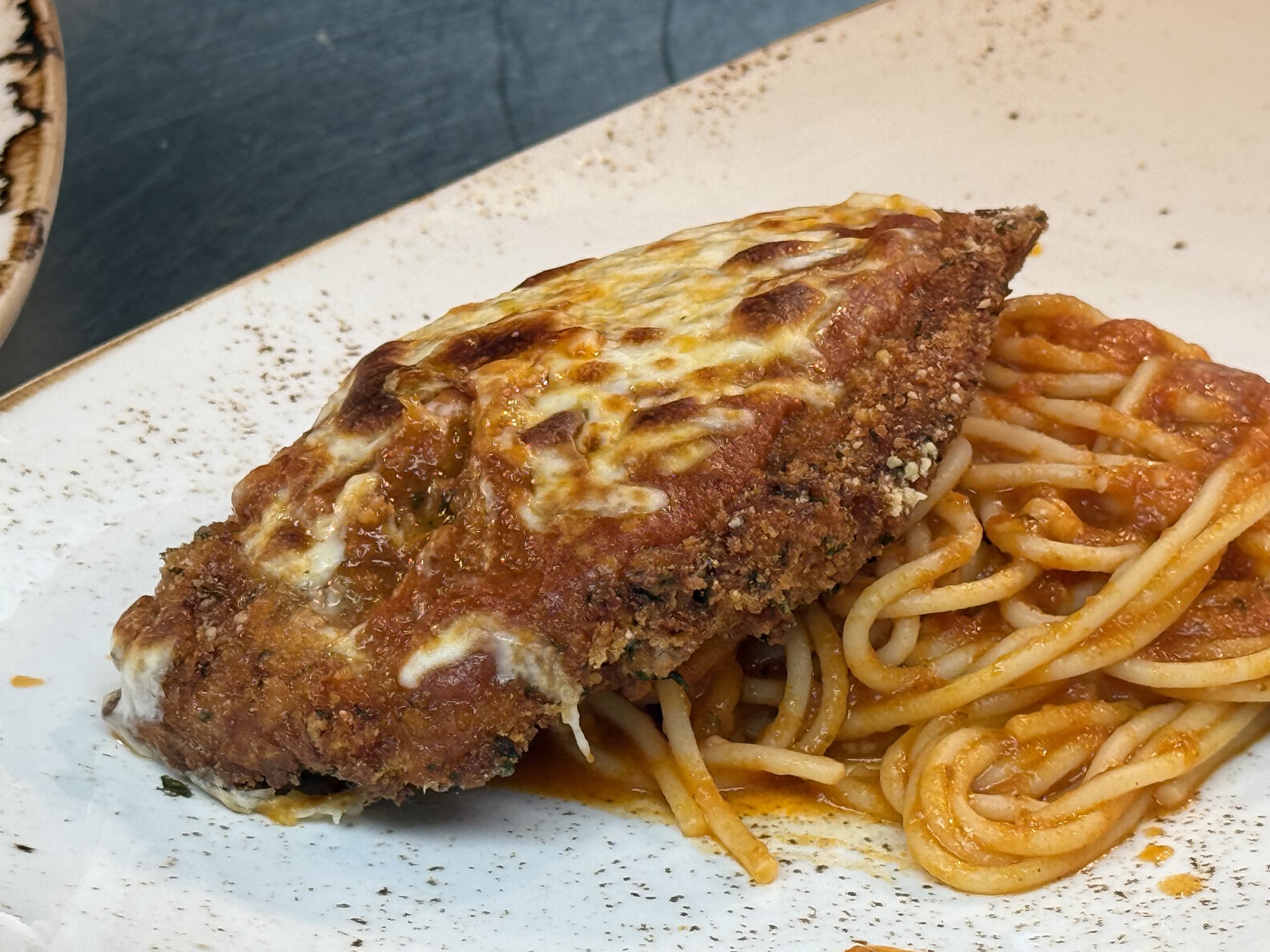 Chicken parmigiana with spaghetti on a white plate