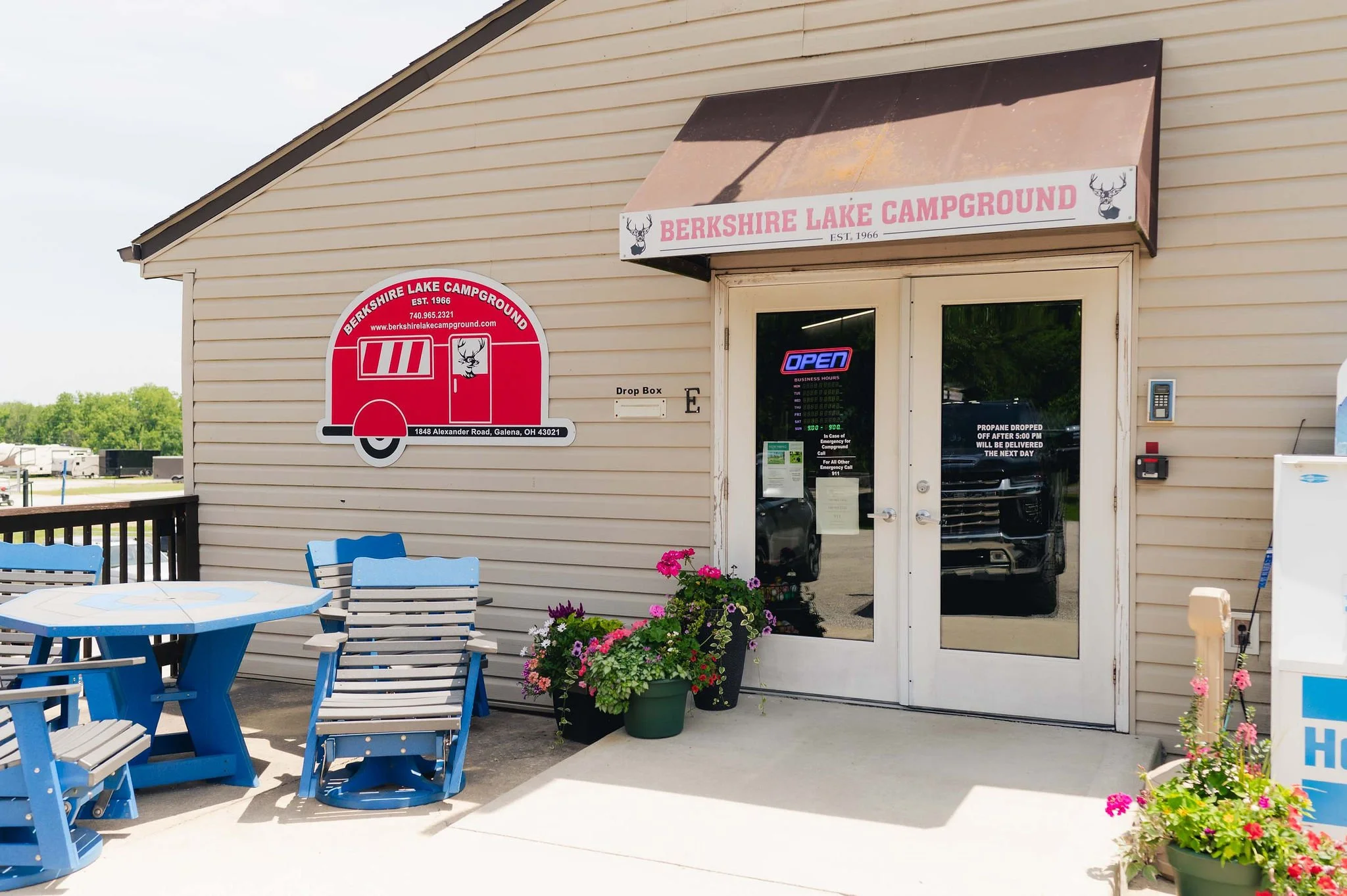 The entrance to Berkshire Lake Campground with a sign, decorated with a deer logo, and a large red camper graphic. The door has a neon