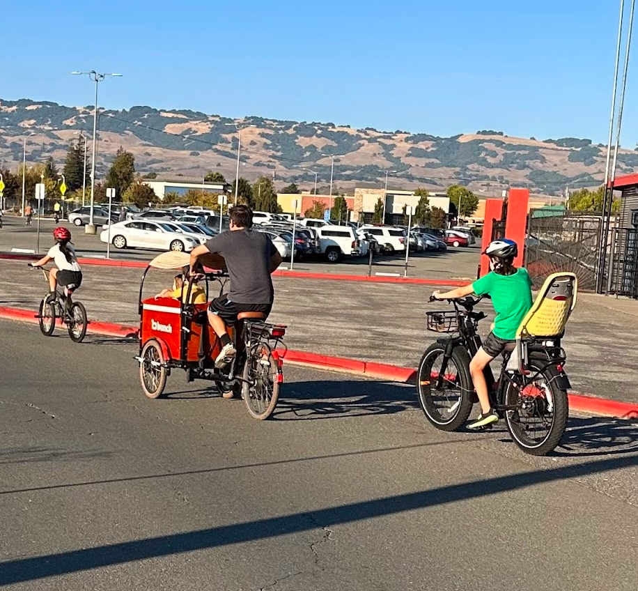 ***Family cargo bikes in front of fairgrounds.png