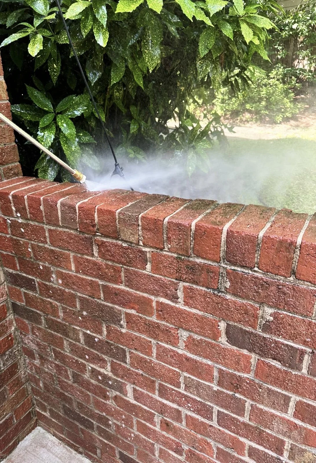 pressure washer to clean a brick wall outdoors