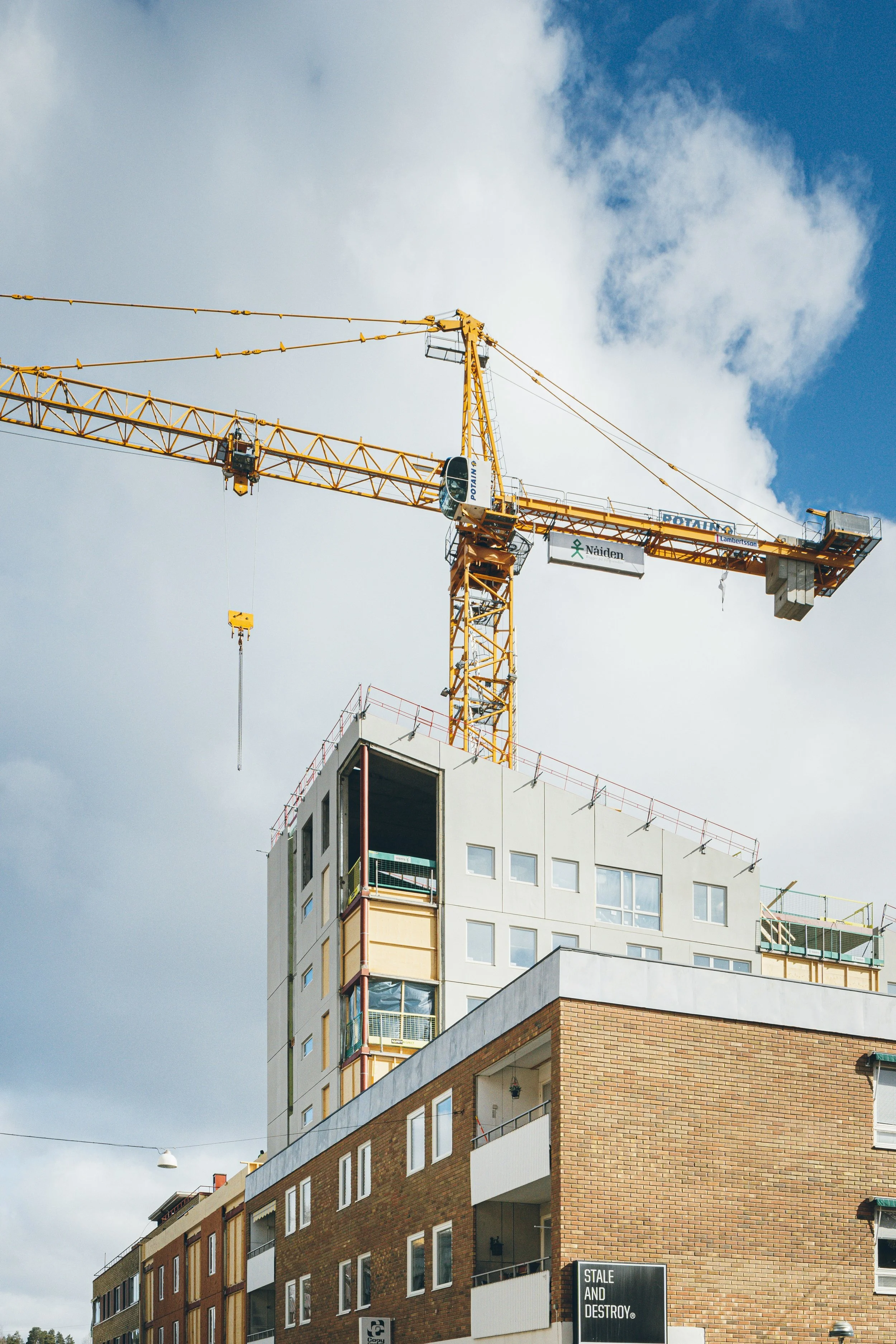 Une grue jaune sur un chantier de construction de bâtiment résidentiel avec un ciel partiellement nuageux