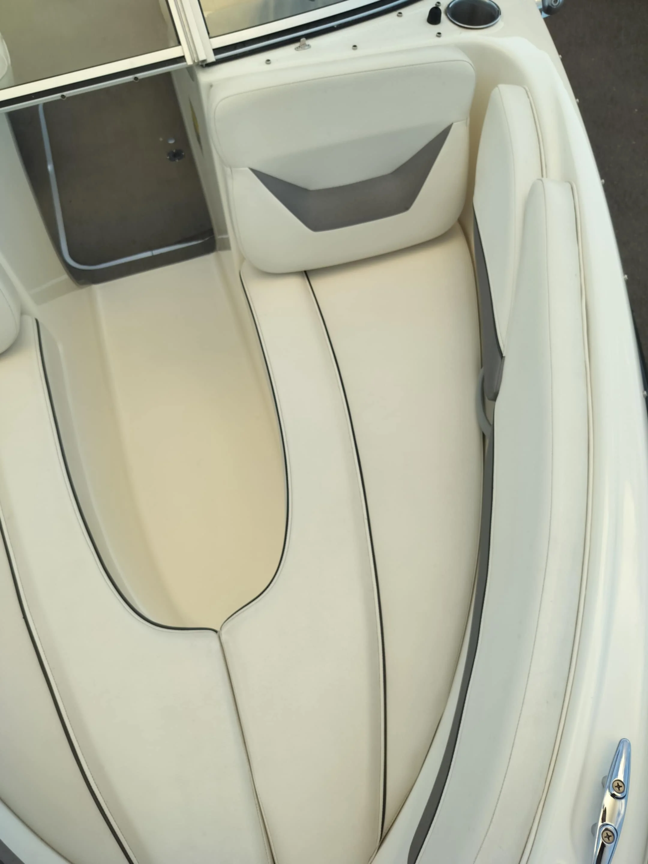 An empty boat with white seating and a built-in storage area at the bow.