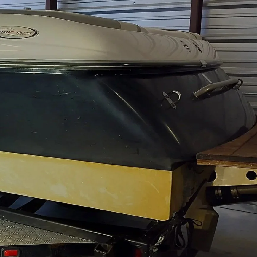A small boat with a yellow bottom on a trailer inside a storage unit.