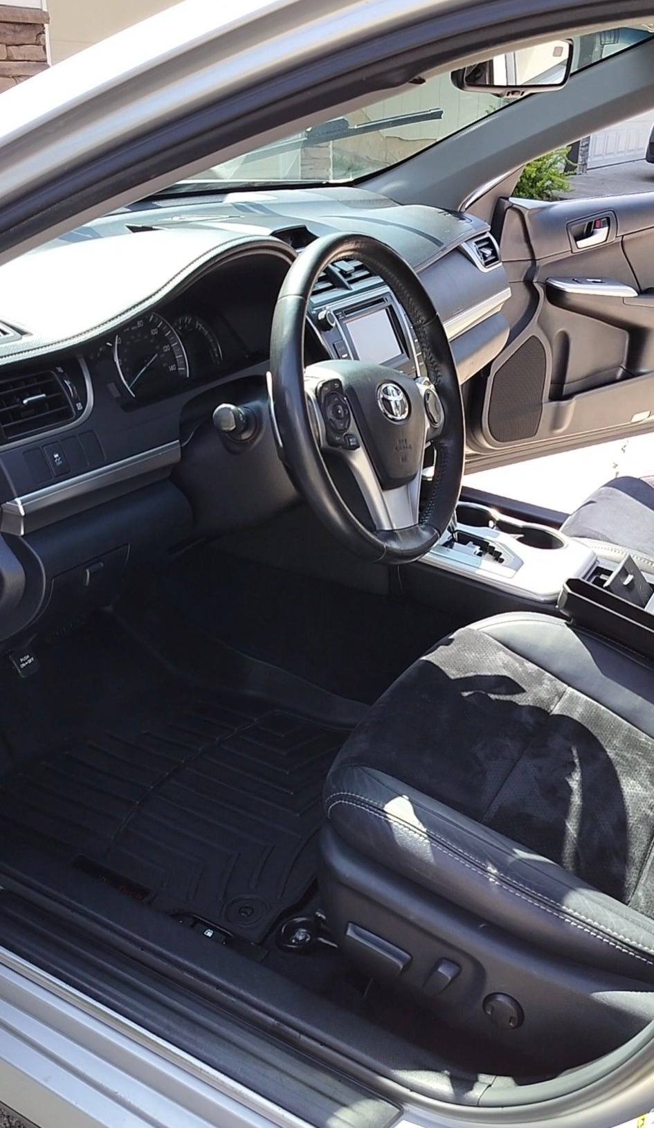 Interior of a Toyota car showing the steering wheel, dashboard, driver's seat, and center console.