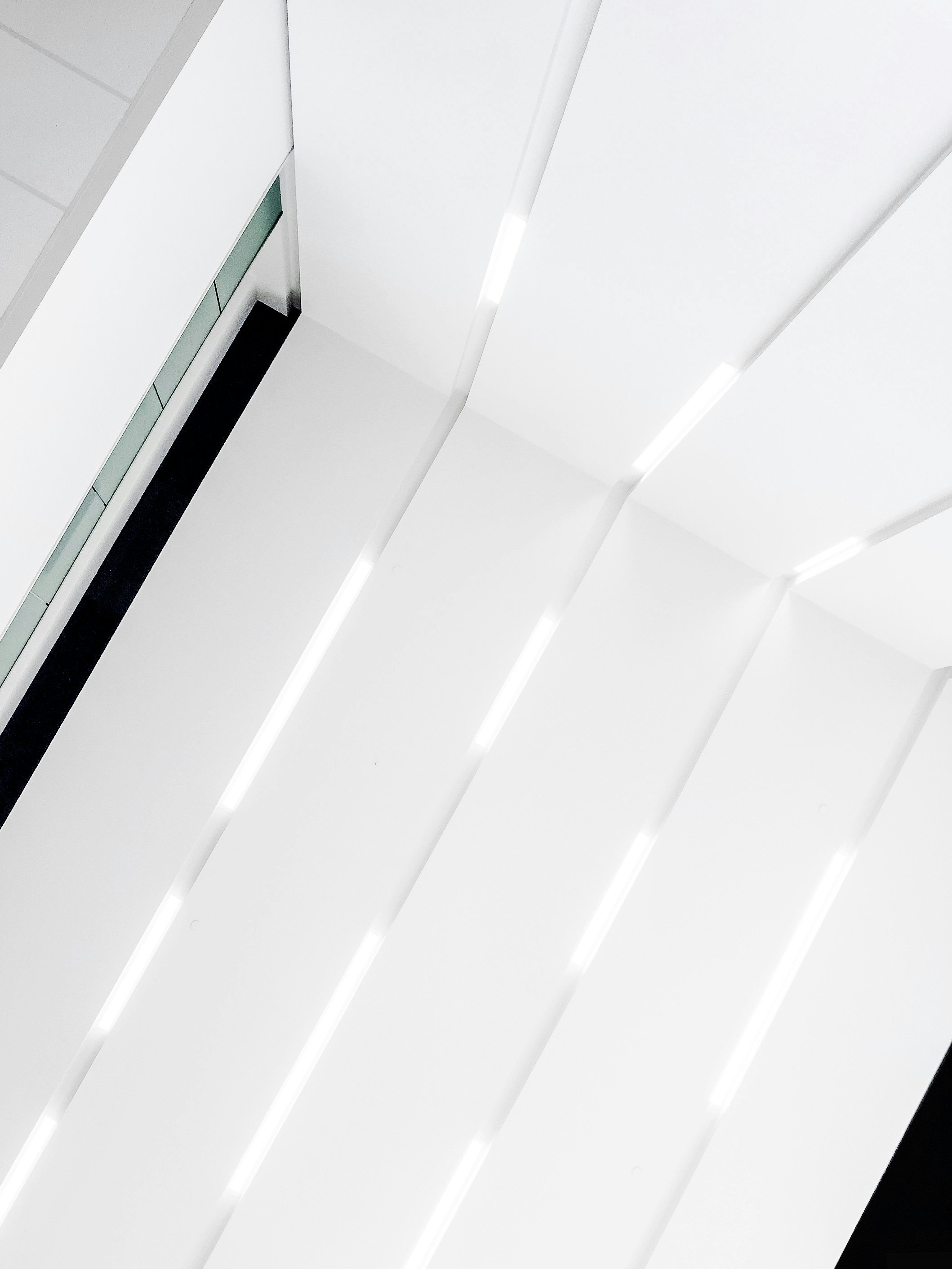 A view of an elevator interior with white walls and vertical lighting strips.
