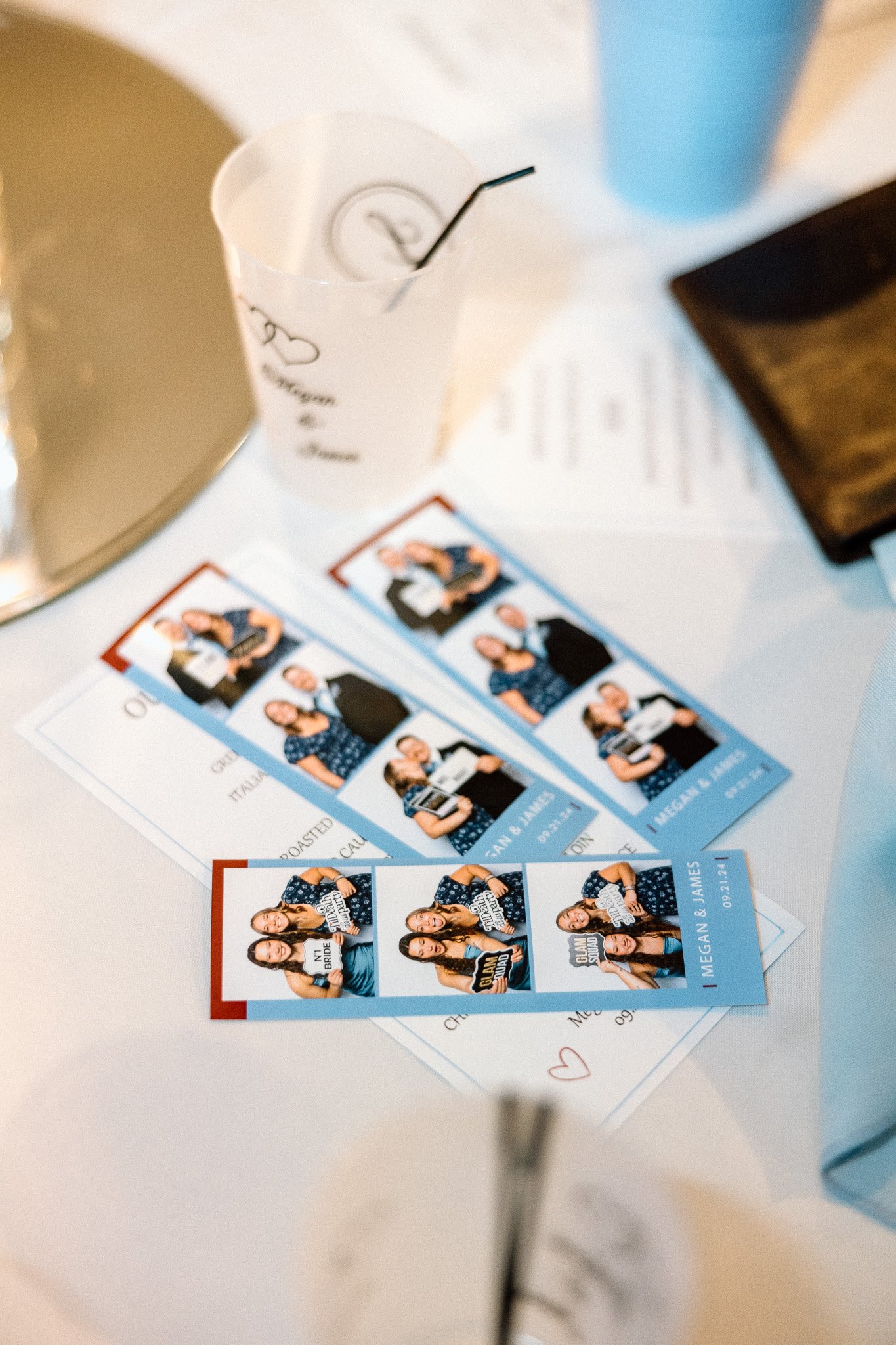 Photo of photo booth strips featuring four women. The strips are placed on a white table alongside a cup with a straw, a wallet, and some papers.