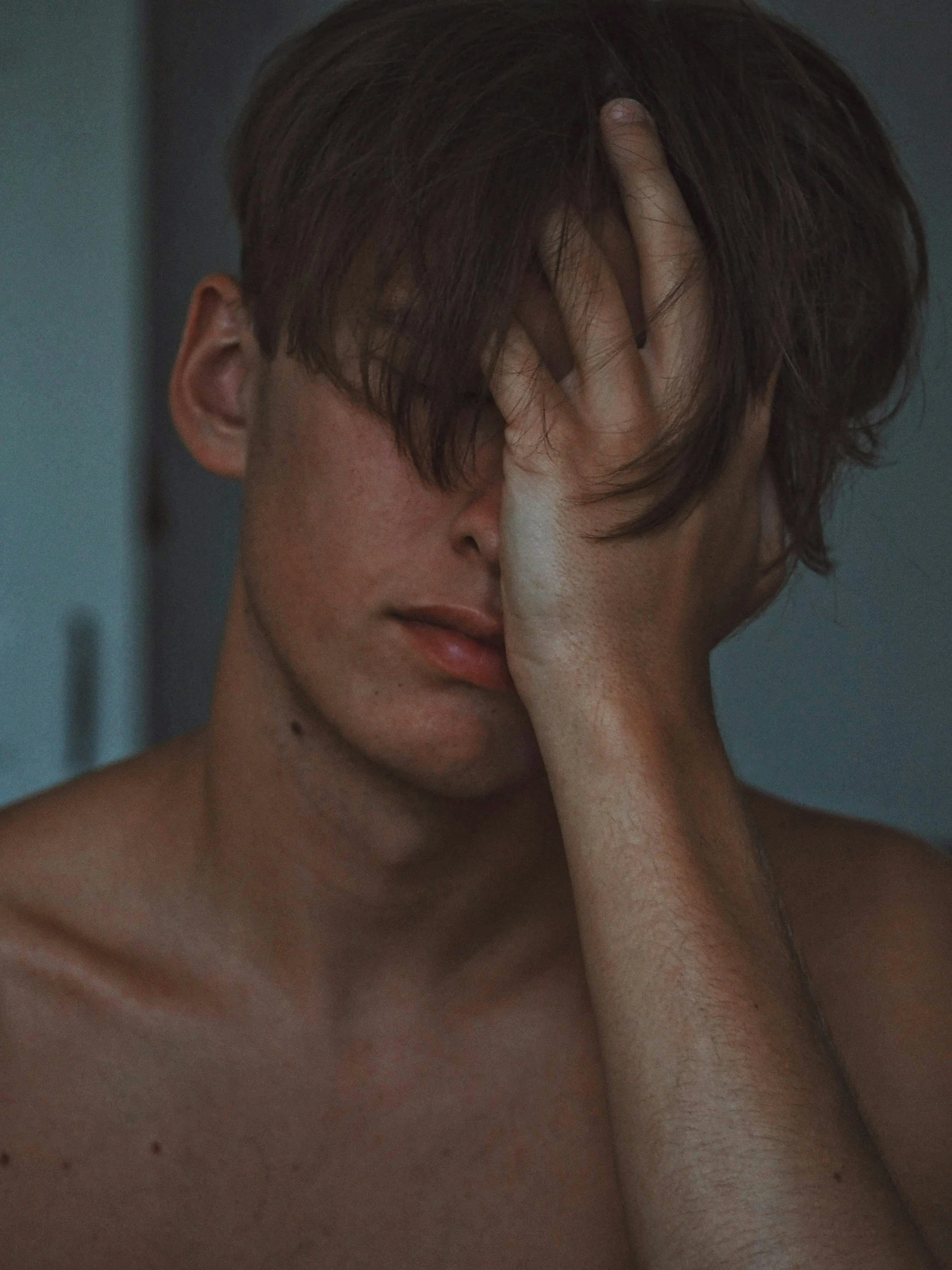 Young person with short brown hair and fair skin, covering their face with one hand, showing a distressed or contemplative expression. Hangover. IV. Vitamin IV. Seattle. Bellevue. Kirkland