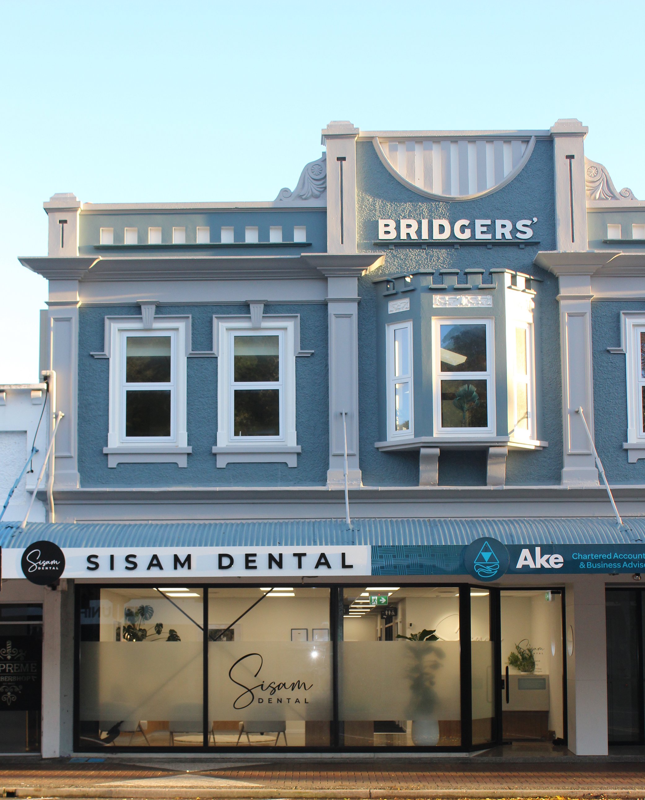 A two-story building with a dental office on the ground floor and a sign reading 'BRIDGERS' on the upper facade, with a bright sky above.