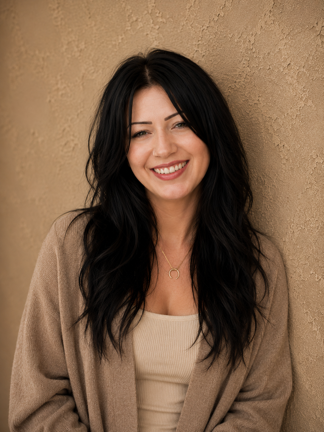A young woman with shoulder-length brown hair smiling outdoors near a body of water and open landscape.