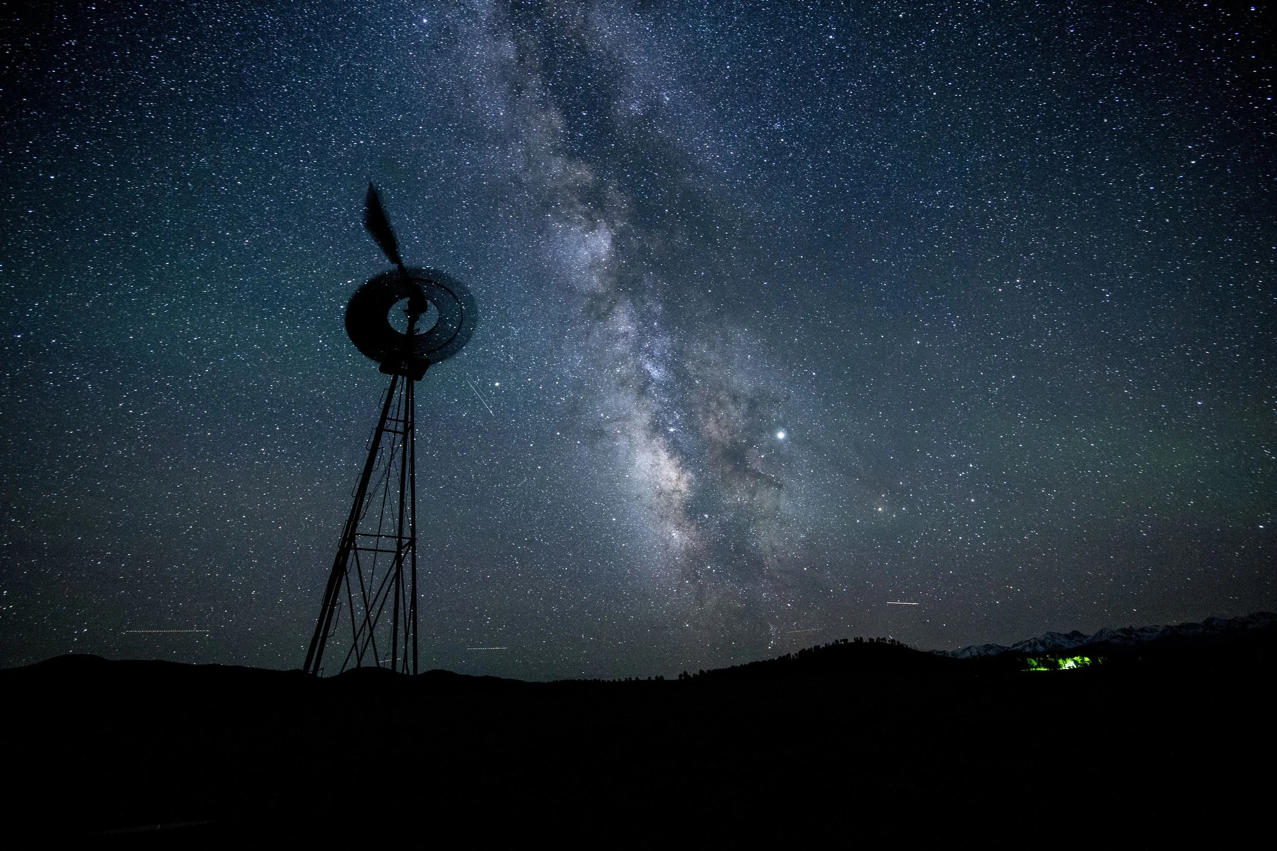 Silhouette of a windmill against a starry night sky with the Milky Way galaxy visible.