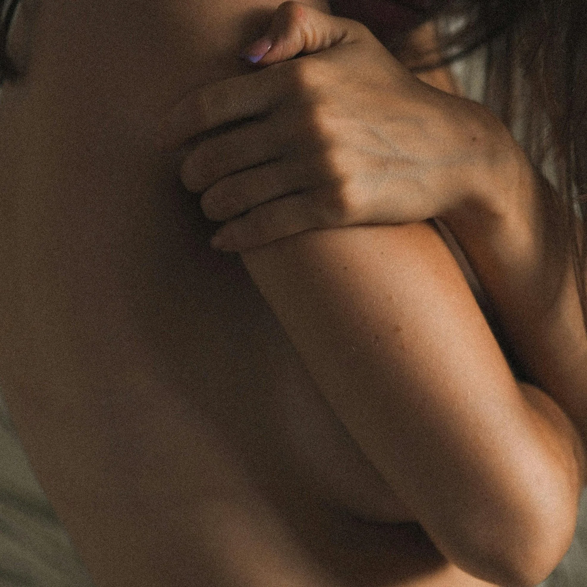 Close-up of a person's face and hand, focusing on lips and cheek, with the person lying down on a textured surface.