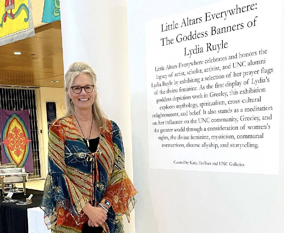 Katie Hoffner stands in front of gallery with Lydia Ruyle's goddess art at University of Northern Colorado
