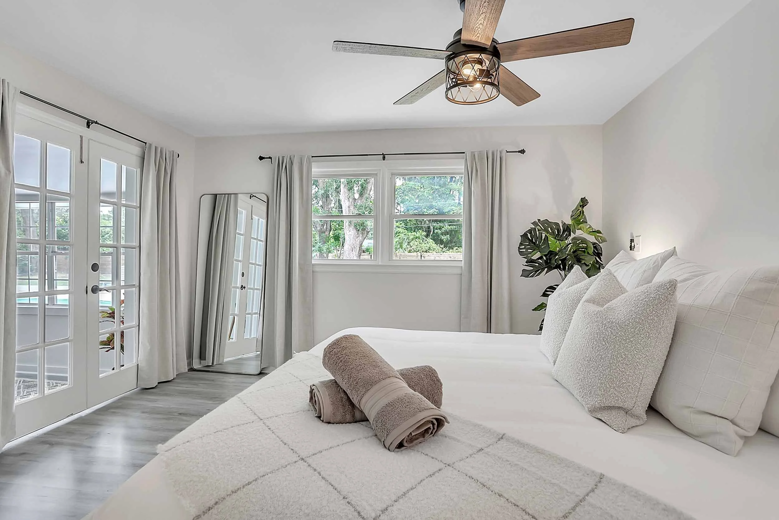 Master suite with king bed, premium Beautyrest hybrid mattress, blackout curtains, cotton linens and towels, variety of pillows, throw blanket, ceiling fan, full-length mirror, french doors to sunroom