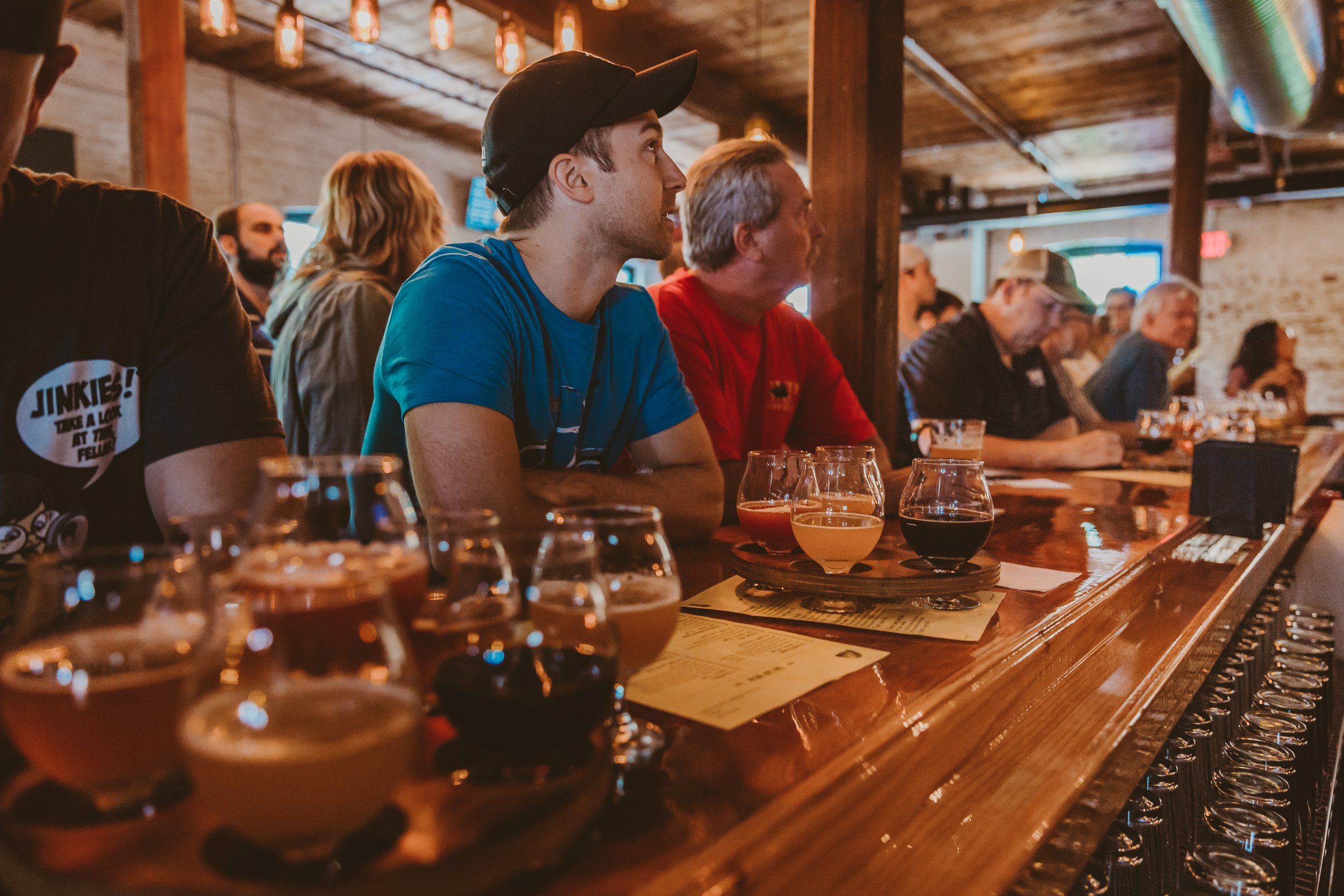 People sitting at a bar tasting various beers.