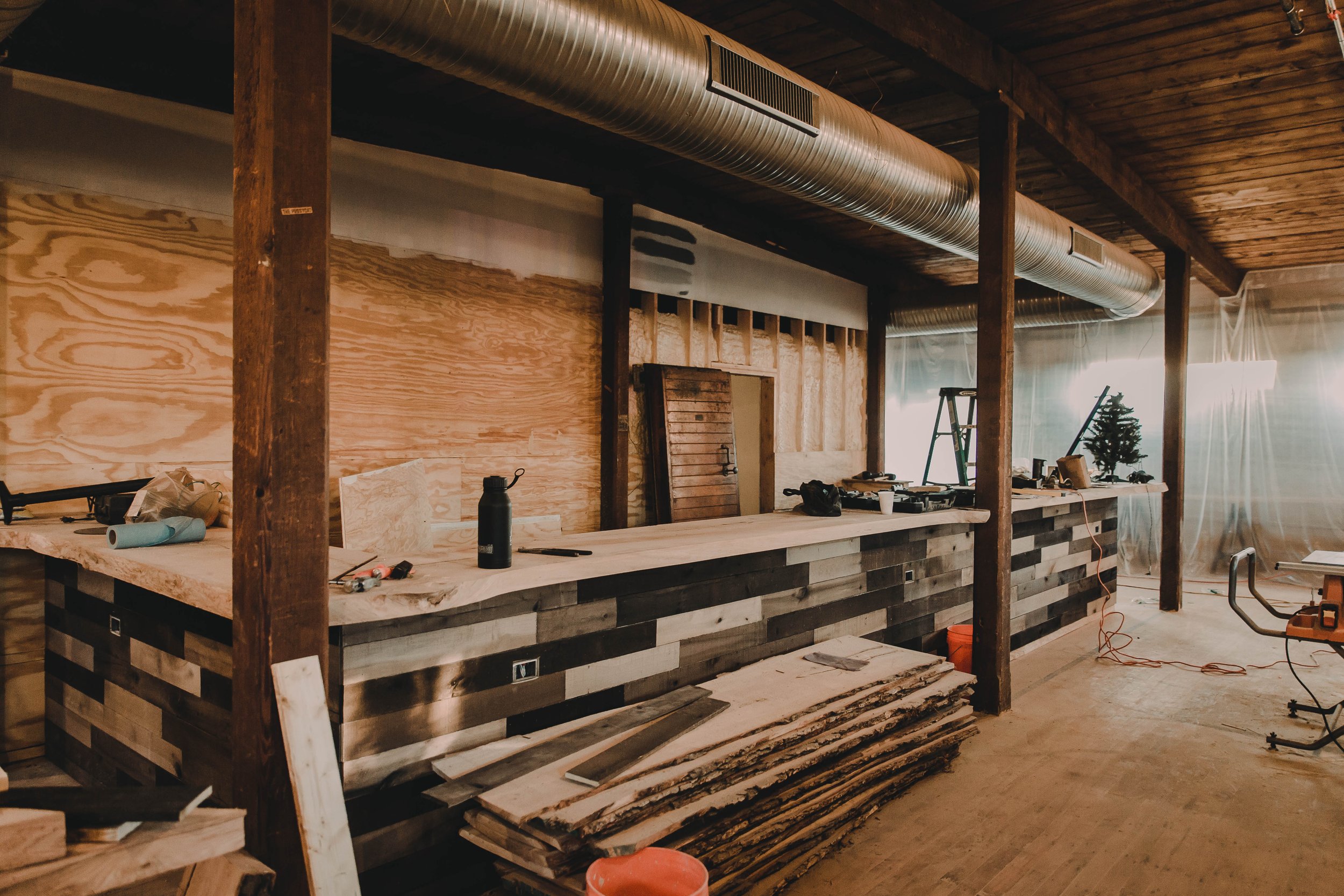 Interior of a construction site with a wooden bar, construction tools, and plywood on the walls and floor.