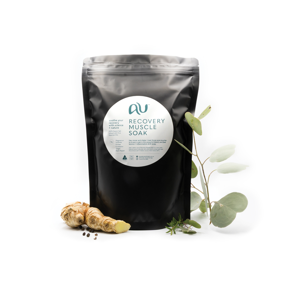 Black 1Kg bag of Abundance Unlimited Recovery Muscle Soak, surrounded by ginger and other fresh ingredients