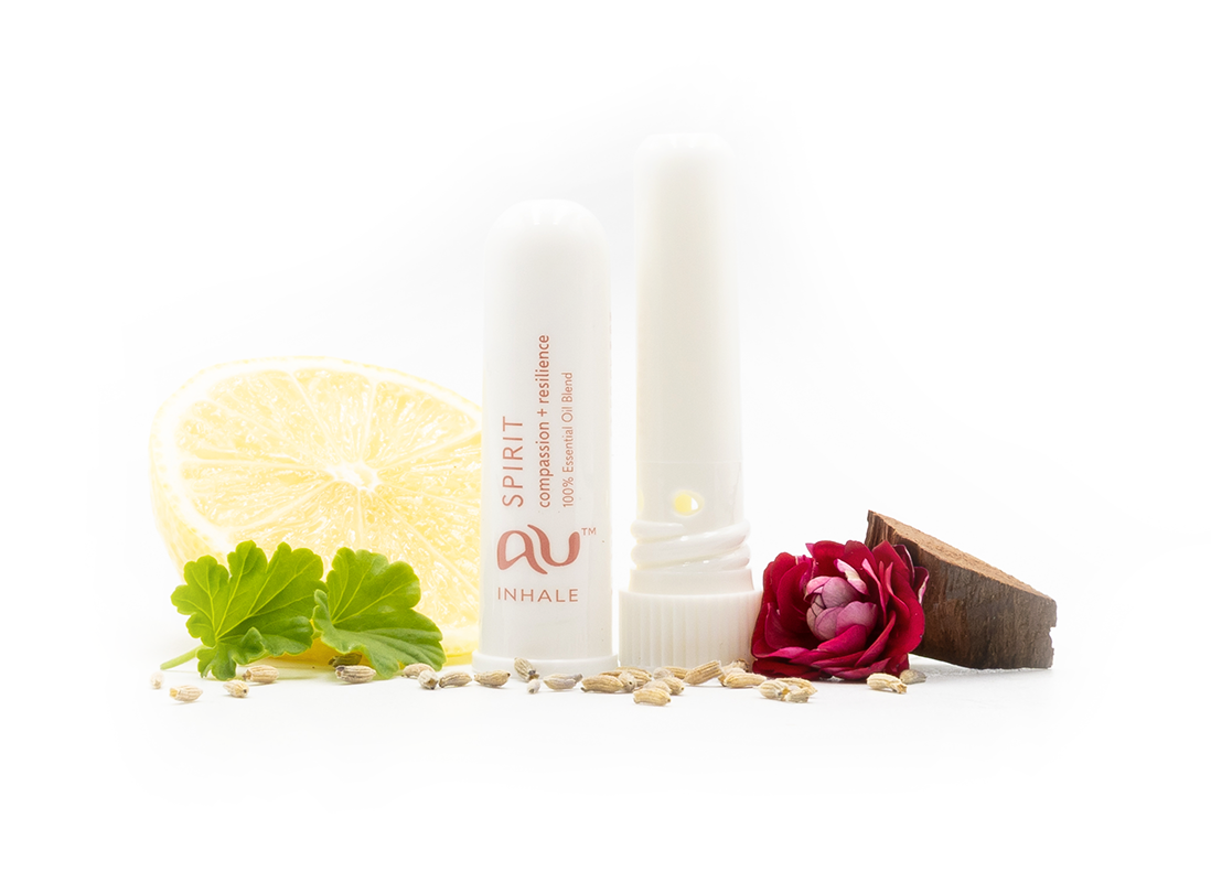 The Spirit Essential Oil inhaler is arranged on a white background, the cap has been taken off and it sitting next to the inhaler, surrounded by its ingredients - fruit, herbs and spices.