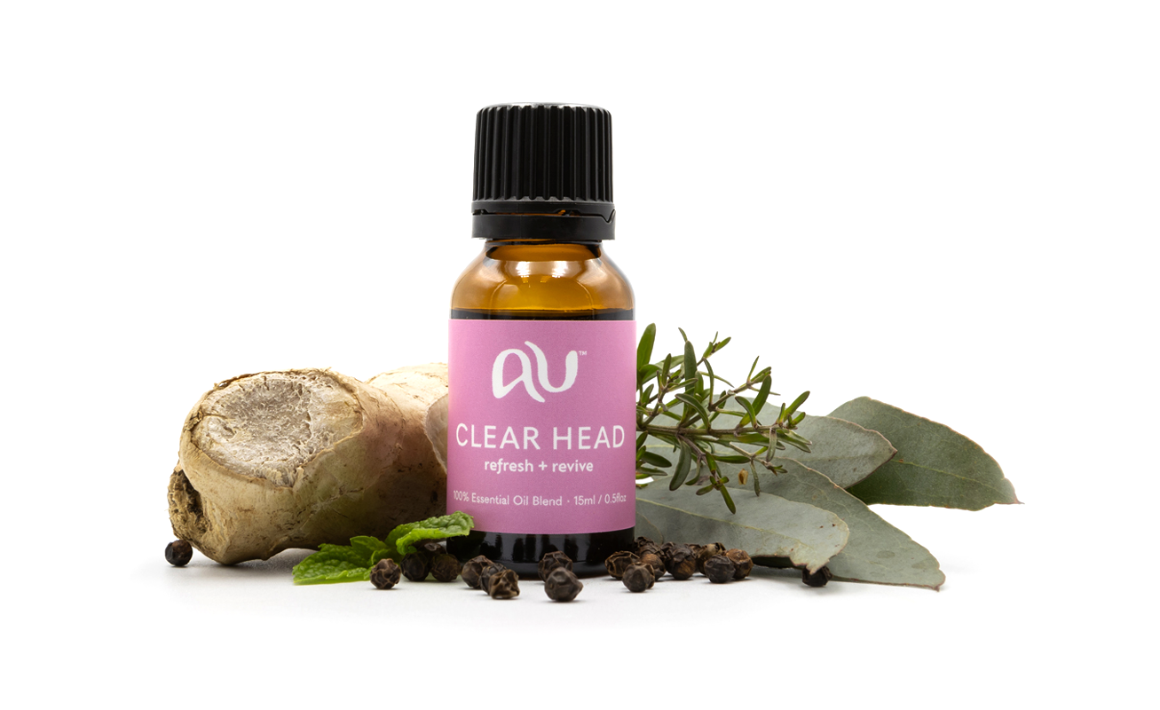 The Clear Head Essential Oil Blend bottle is arranged on a white background surrounded by its ingredients - fruit, herbs and spices.