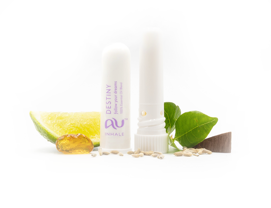 The Destiny Essential Oil inhaler is arranged on a white background, the cap has been taken off and it sitting next to the inhaler, surrounded by its ingredients - fruit, herbs and spices.