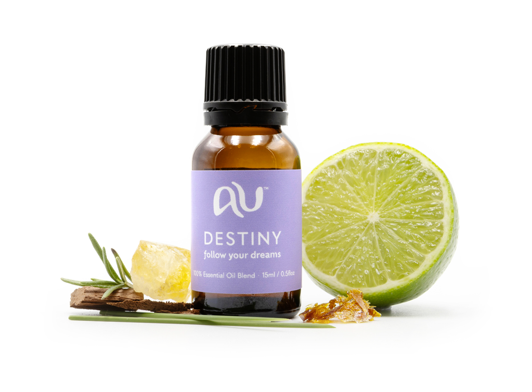 The Destiny Essential Oil Blend bottle is arranged on a white background surrounded by its ingredients - fruit, herbs and spices.