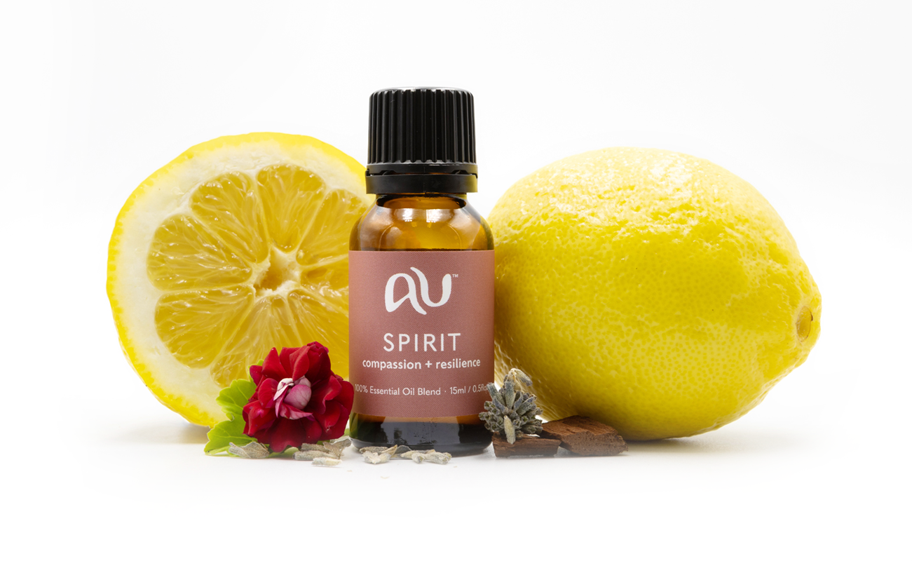 The Spirit Essential Oil Blend bottle is arranged on a white background surrounded by its ingredients - fruit, herbs and spices.