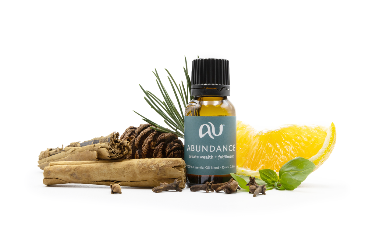 The Abundance Essential Oil Blend bottle is arranged on a white background surrounded by its ingredients - fruit, herbs and spices