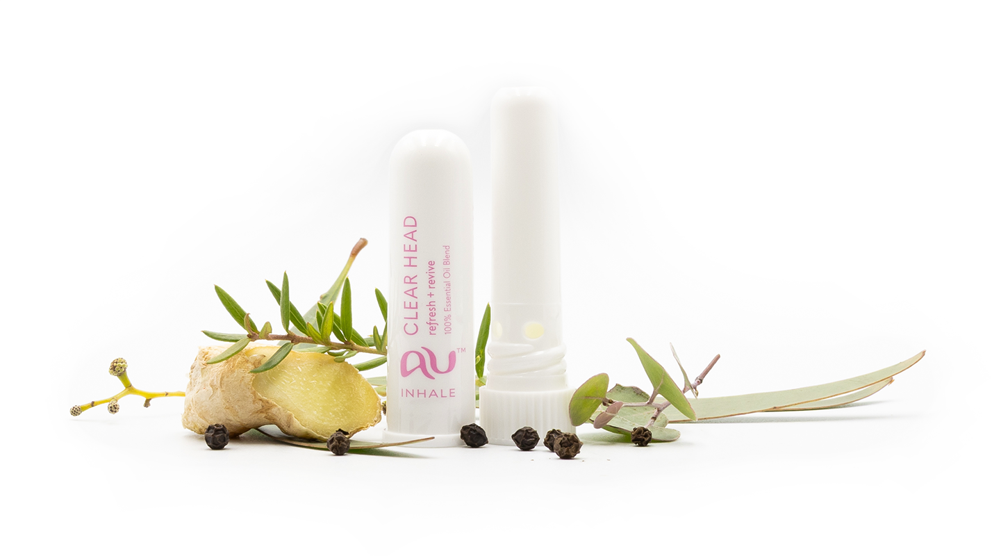 The Clear Head Essential Oil inhaler is arranged on a white background, the cap has been taken off and it sitting next to the inhaler, surrounded by its ingredients - fruit, herbs and spices.