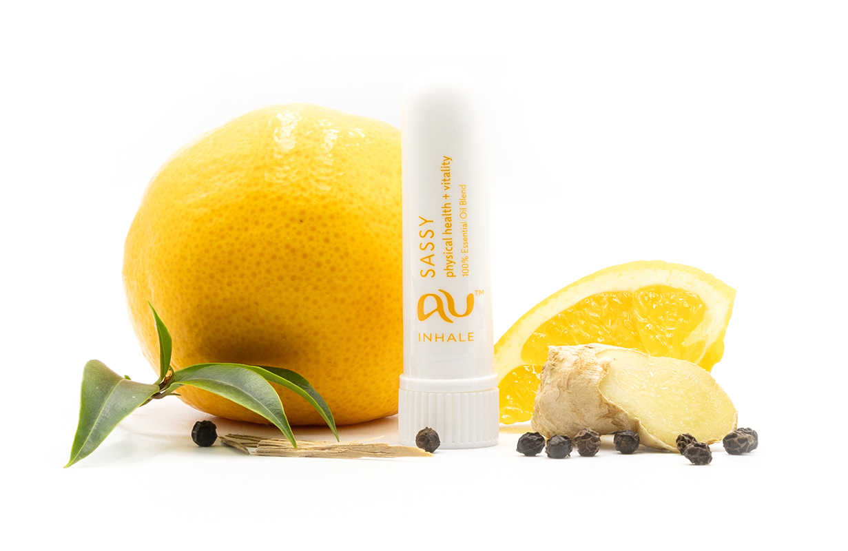 The Sassy Essential Oil inhaler is arranged on a white background surrounded by its ingredients - fruit, herbs and spices.
