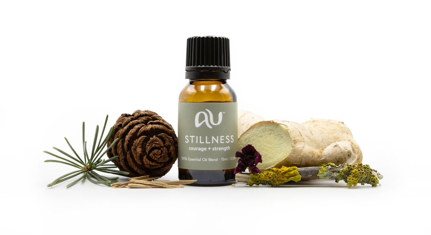 The Stillness Essential Oil Blend bottle is arranged on a white background surrounded by its ingredients - fruit, herbs and spices.