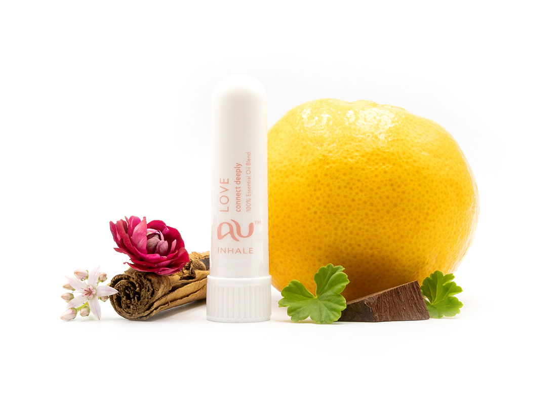 The Love Essential Oil inhaler is arranged on a white background surrounded by its ingredients - fruit, herbs and spices.