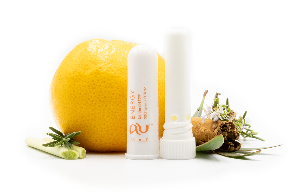 The Energy Essential Oil inhaler is arranged on a white background, the cap has been taken off and it sitting next to the inhaler, surrounded by its ingredients - fruit, herbs and spices.