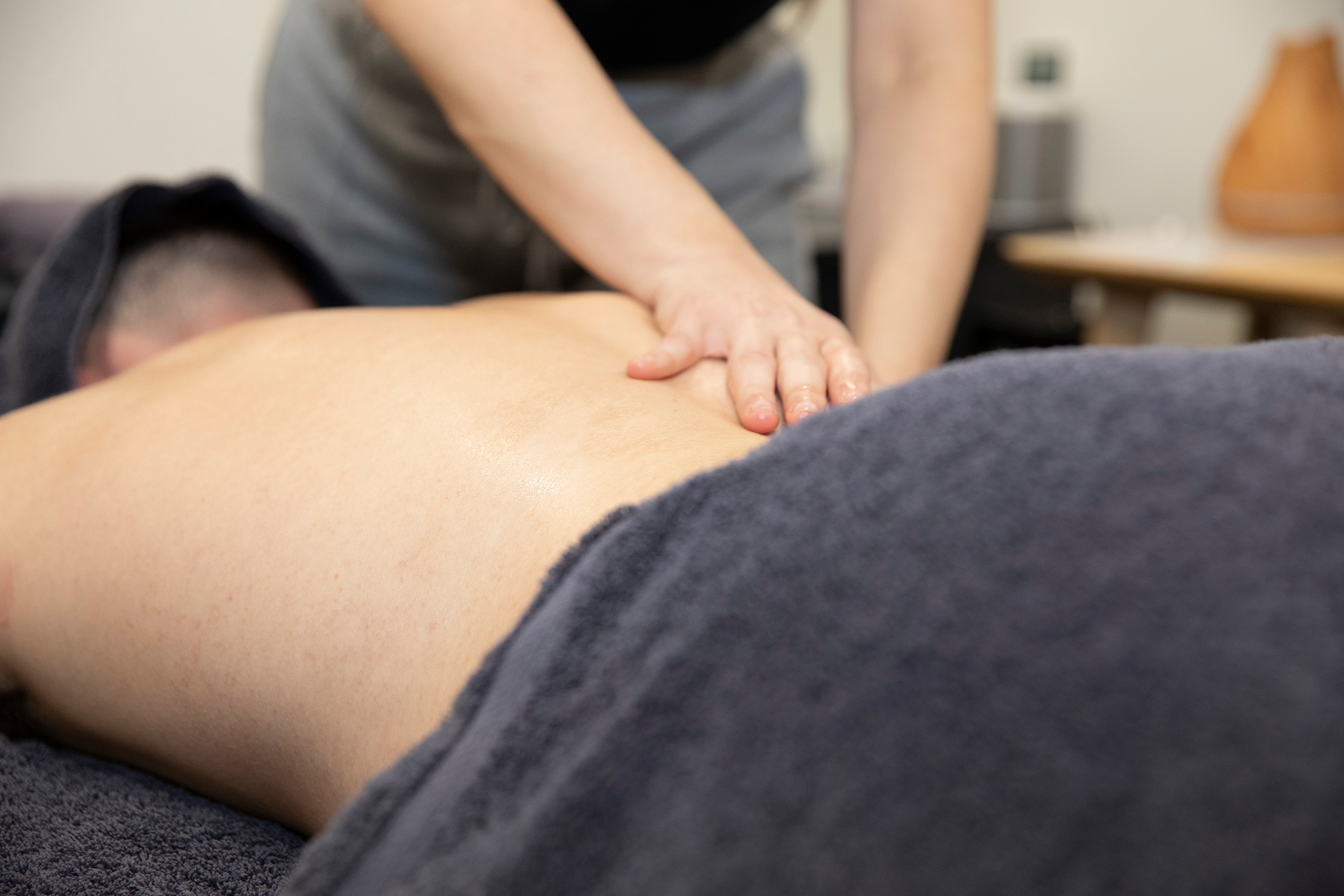 A client receiving a massage from a practitioner on the lower back