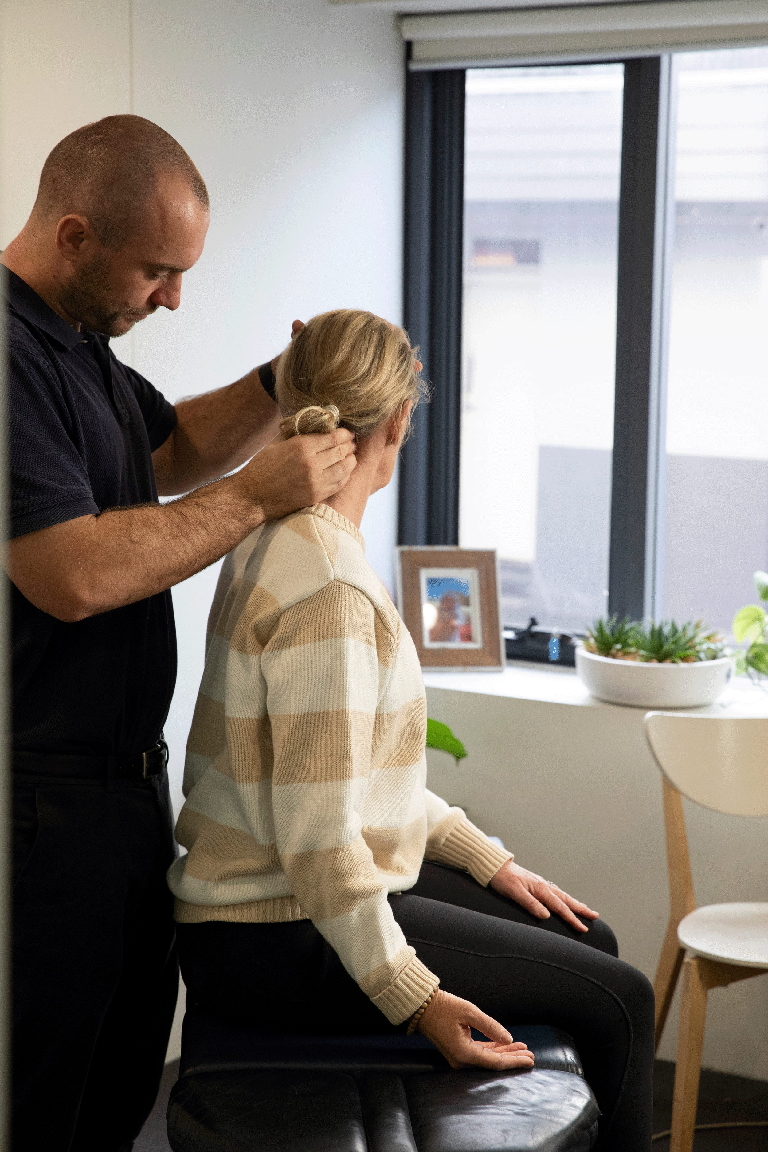 Chiropractor helping a seated client stretch their neck