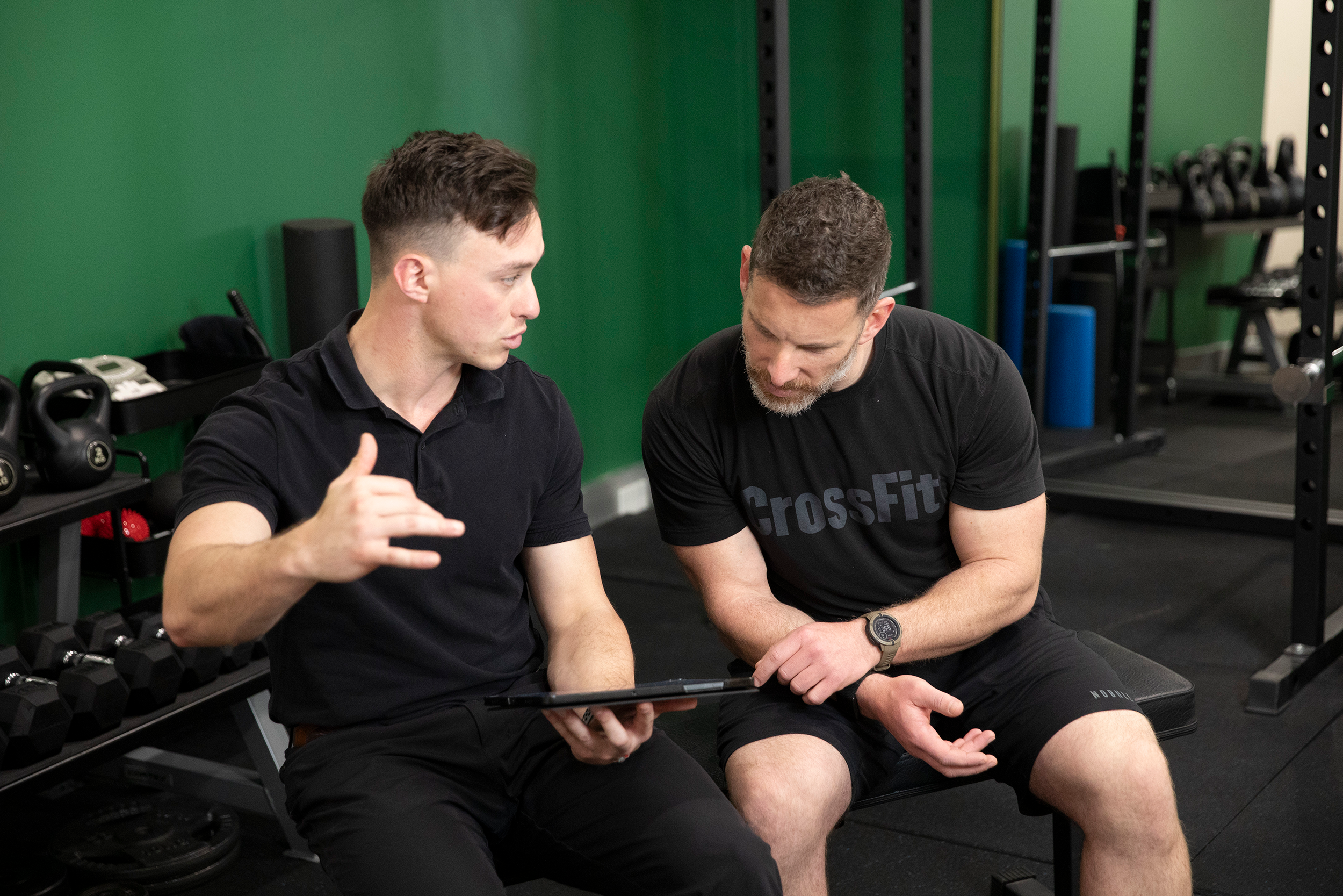 A practitioner and a client reviewing workout plans in clinic gym