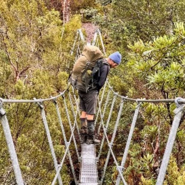 hiker on river crossing bridge near pine valley