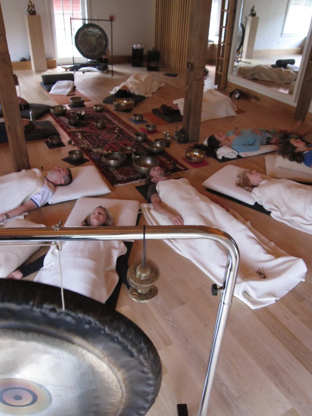 People meditating during a sound healing session at Charym Yoga Studio in Litchfield, Connecticut with gongs and singing bowls in a peaceful room.