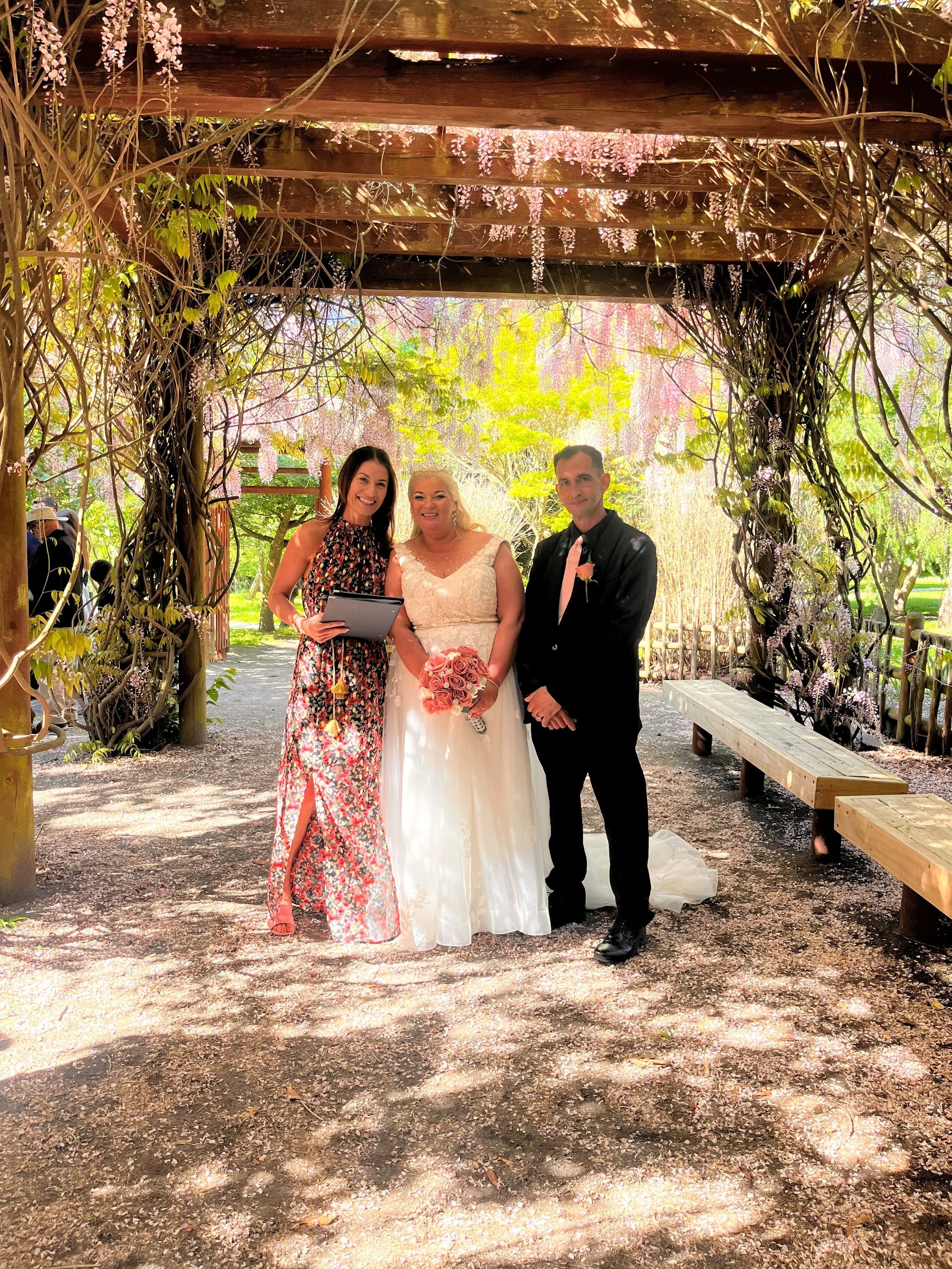 Celebrant Ollie van der Pol with a couple at their wedding ceremony at Halswell Quarry surrounded by spring blossoms.