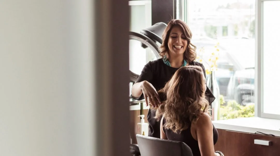 Women getting a hair style in a salon with large windows