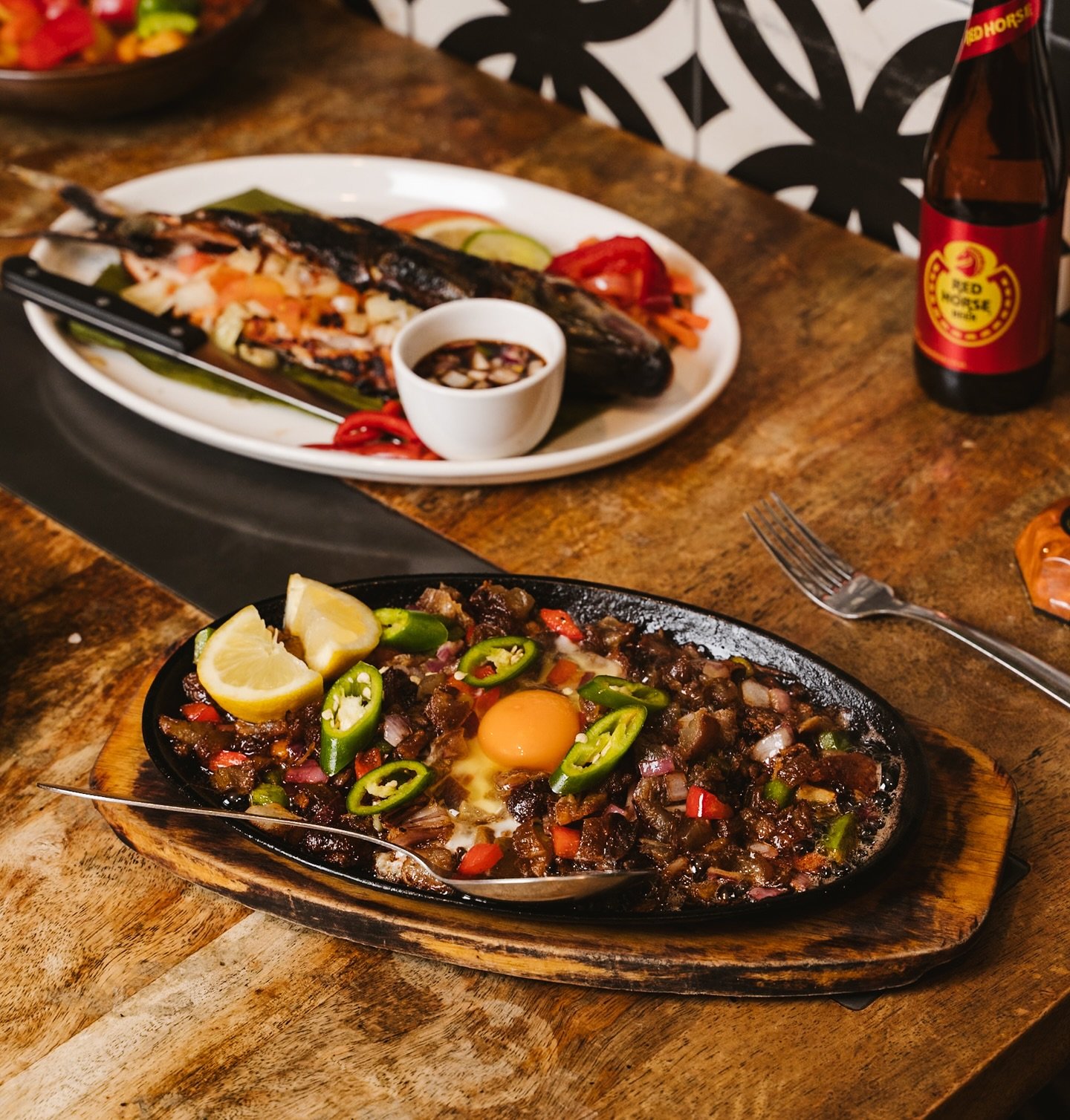 Sizzle. Crunch. Flavour.🔥
Our Sizzling Pork Sisig is the ultimate Filipino pulutan, served hot on a sizzling plate, topped with fresh chillies and a runny egg. Every bite is a punch of savoury, tangy, and crispy goodness.

Whether you pair it with g