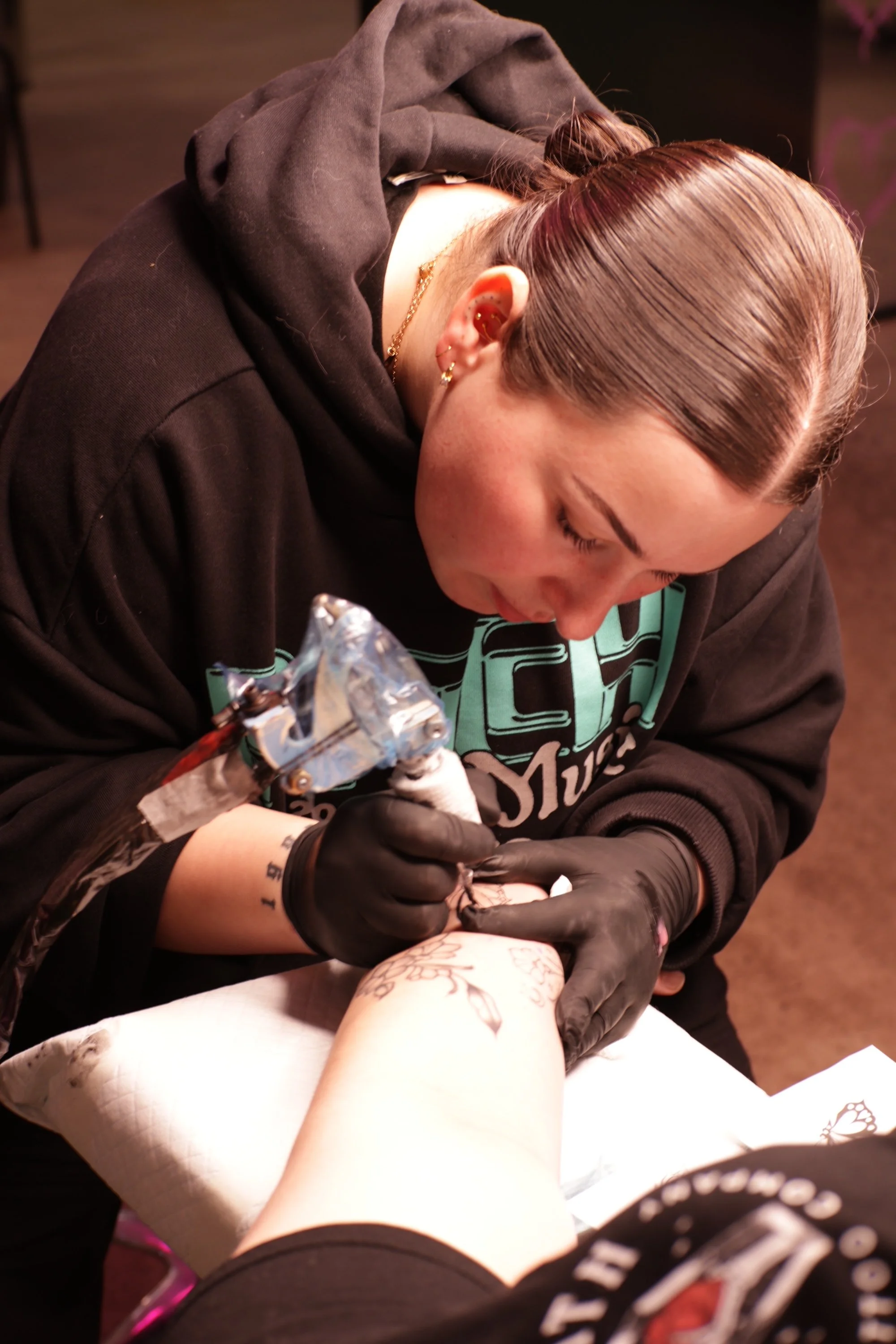 A person receiving a tattoo on their arm from a tattoo artist.