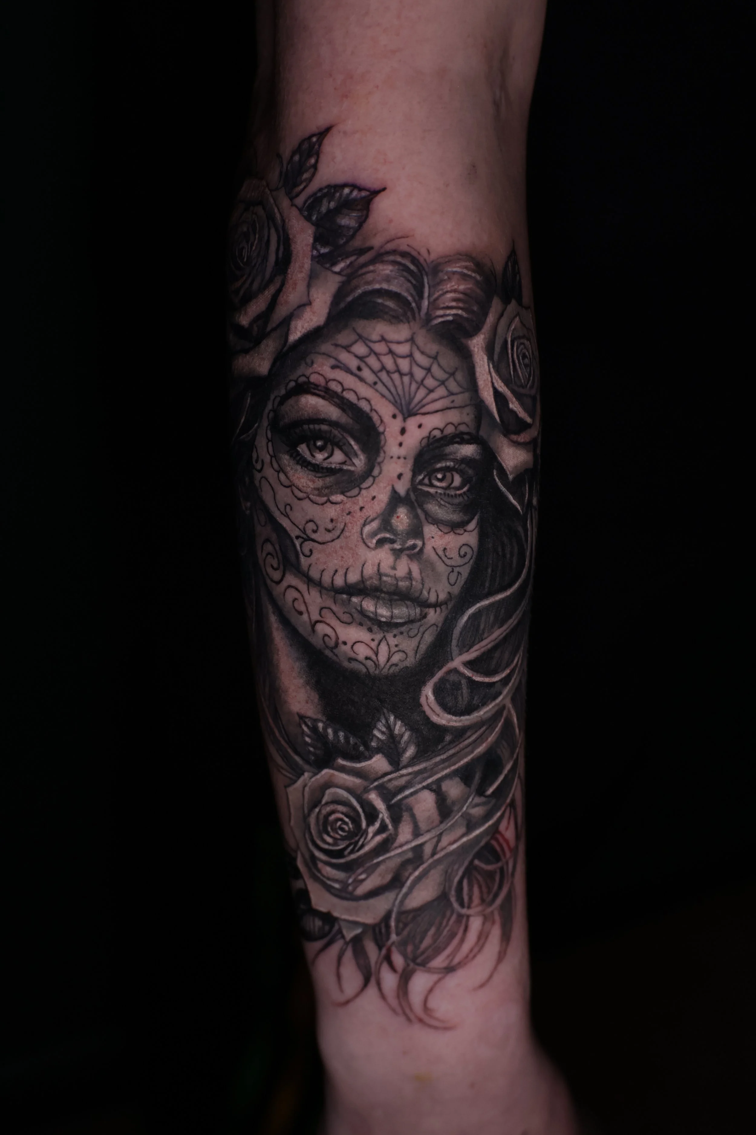 Black and gray tattoo sleeve featuring a woman's face with detailed eyes and lips..