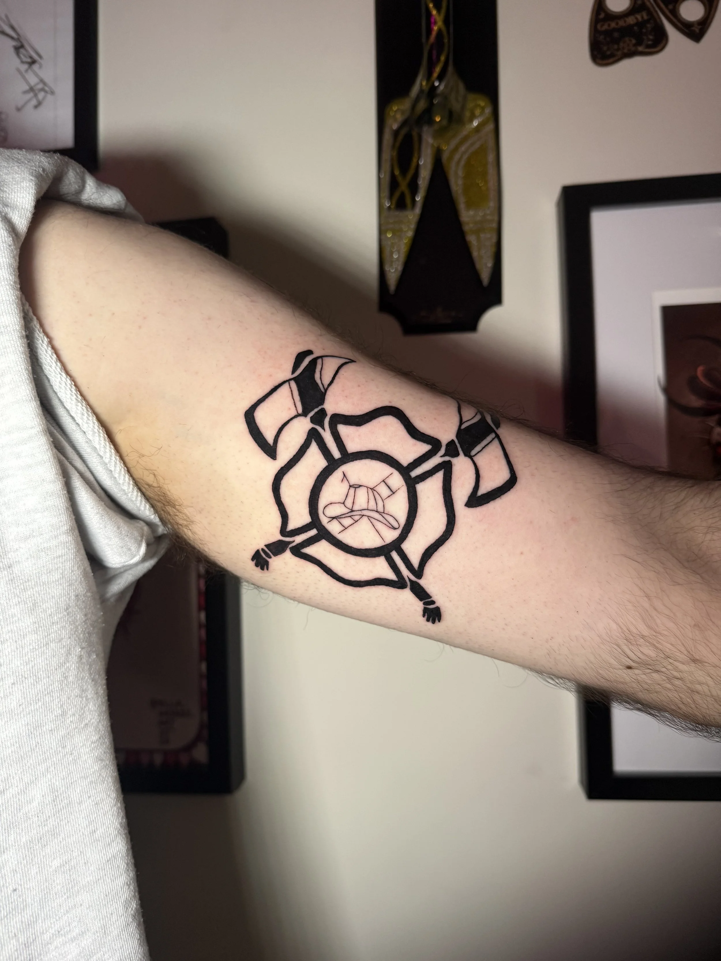 Tattoo of a symbol  on a person's upper arm.