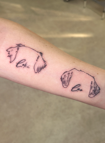 Tattoo of a dog's face outline with the words 'Loki' and 'love' integrated into the design.