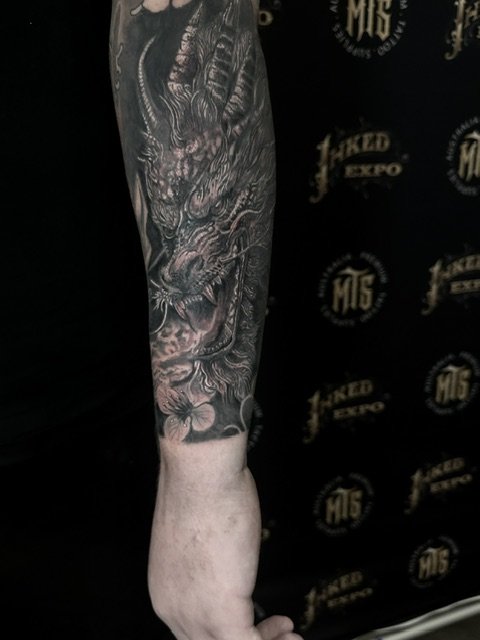 Tattooed arm with a detailed dragon tattoo.